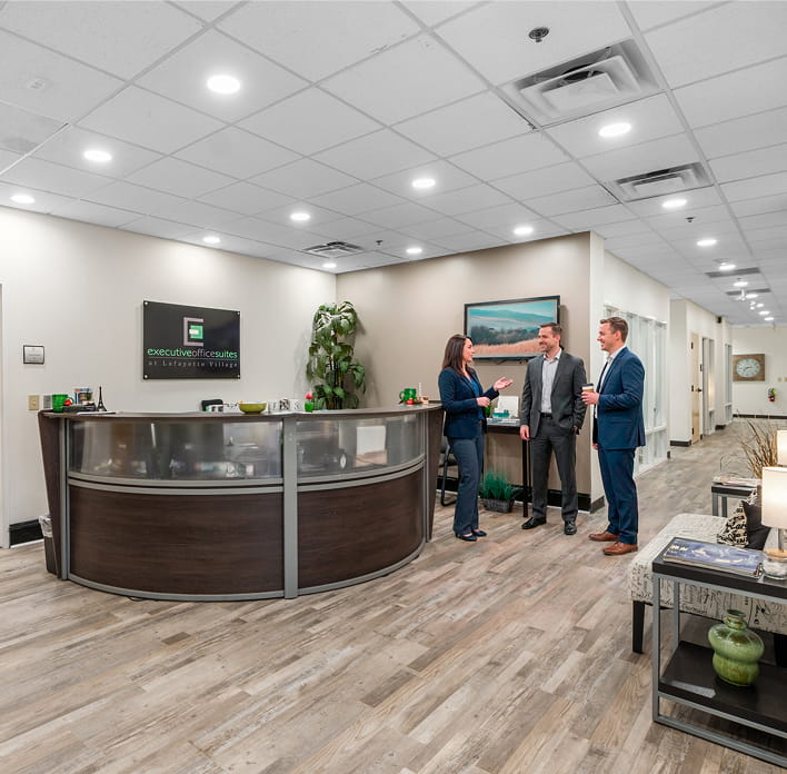 Office reception area with three people talking at the front desk